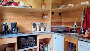 Een kleine keuken met een magnetron, koffiezetapparaat en een wasmachine.