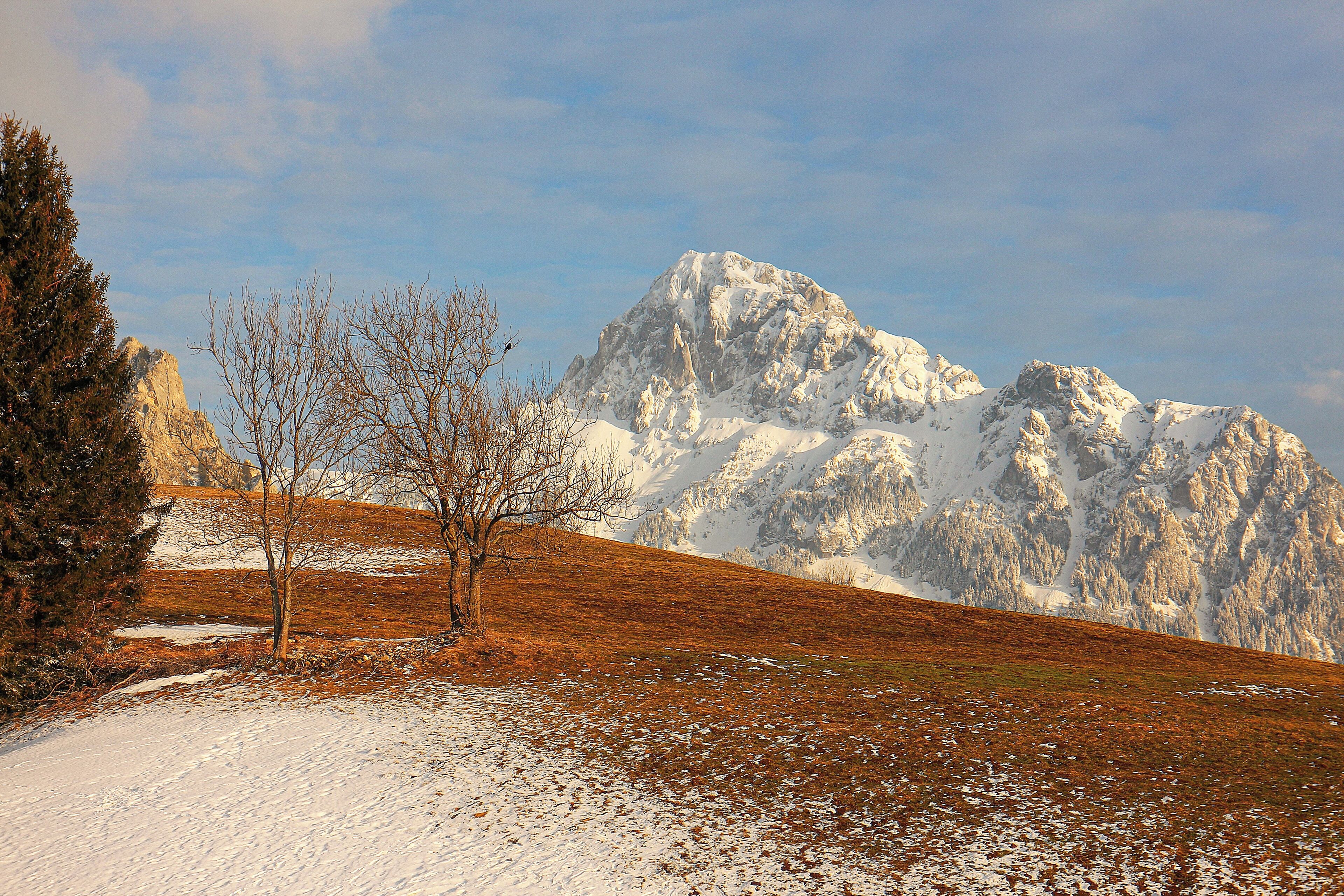 A mountainous landscape with snow-covered peaks and a clear sky.