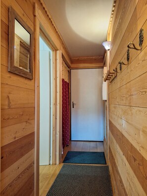 A wooden hallway with a door, a mirror, and a light fixture. - Beautiful mountain accommodation at 12 km from Lake Geneva (Bernex)