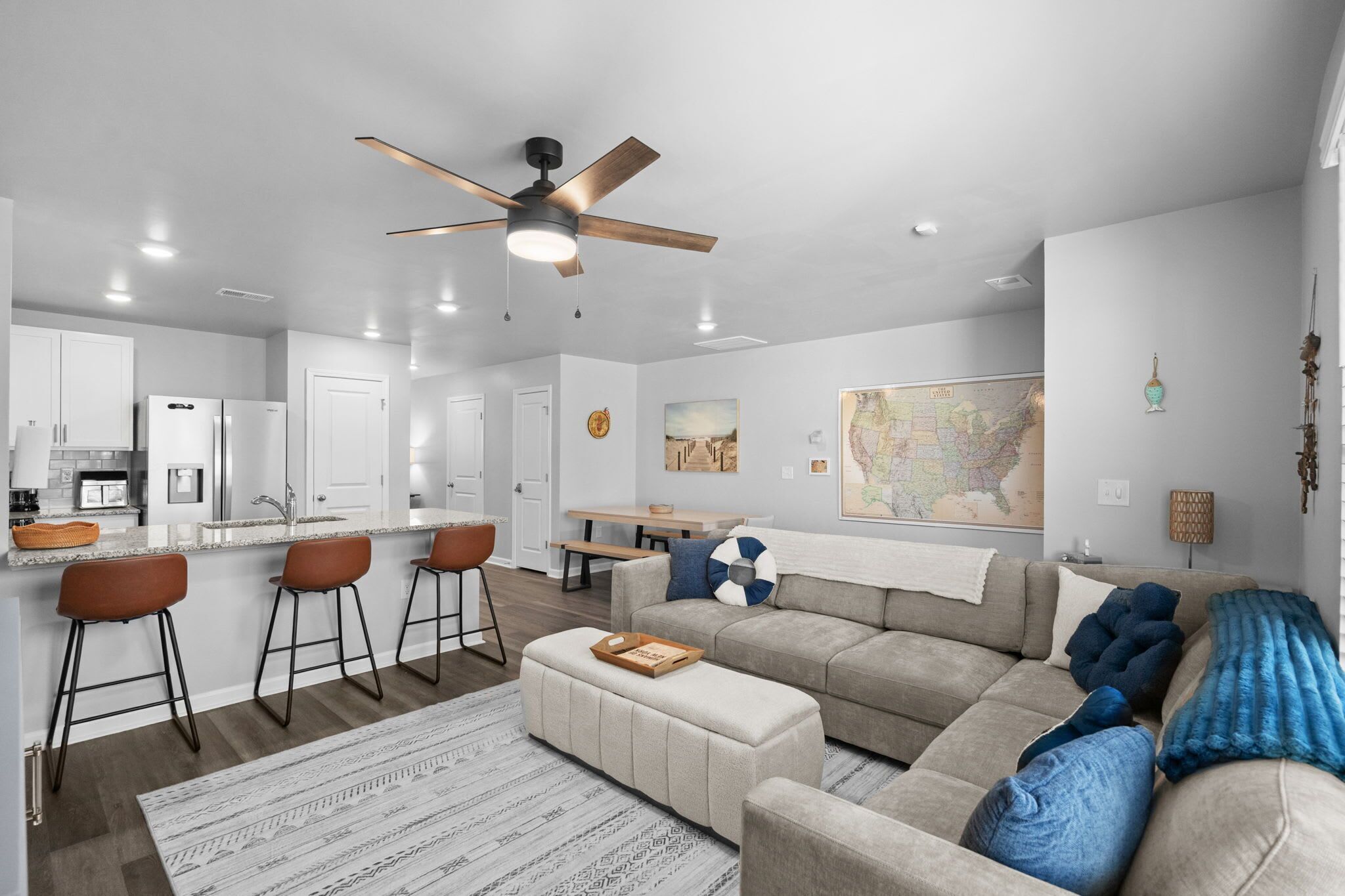 Une cuisine moderne avec des meubles blancs, un grand îlot central doté de tabourets et un ventilateur de plafond.
