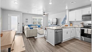A modern kitchen with white cabinets, a stainless steel refrigerator, and a built-in oven. - Tide And Tee Ping Pong Golf Cart By Beach Star (Surfside Beach)