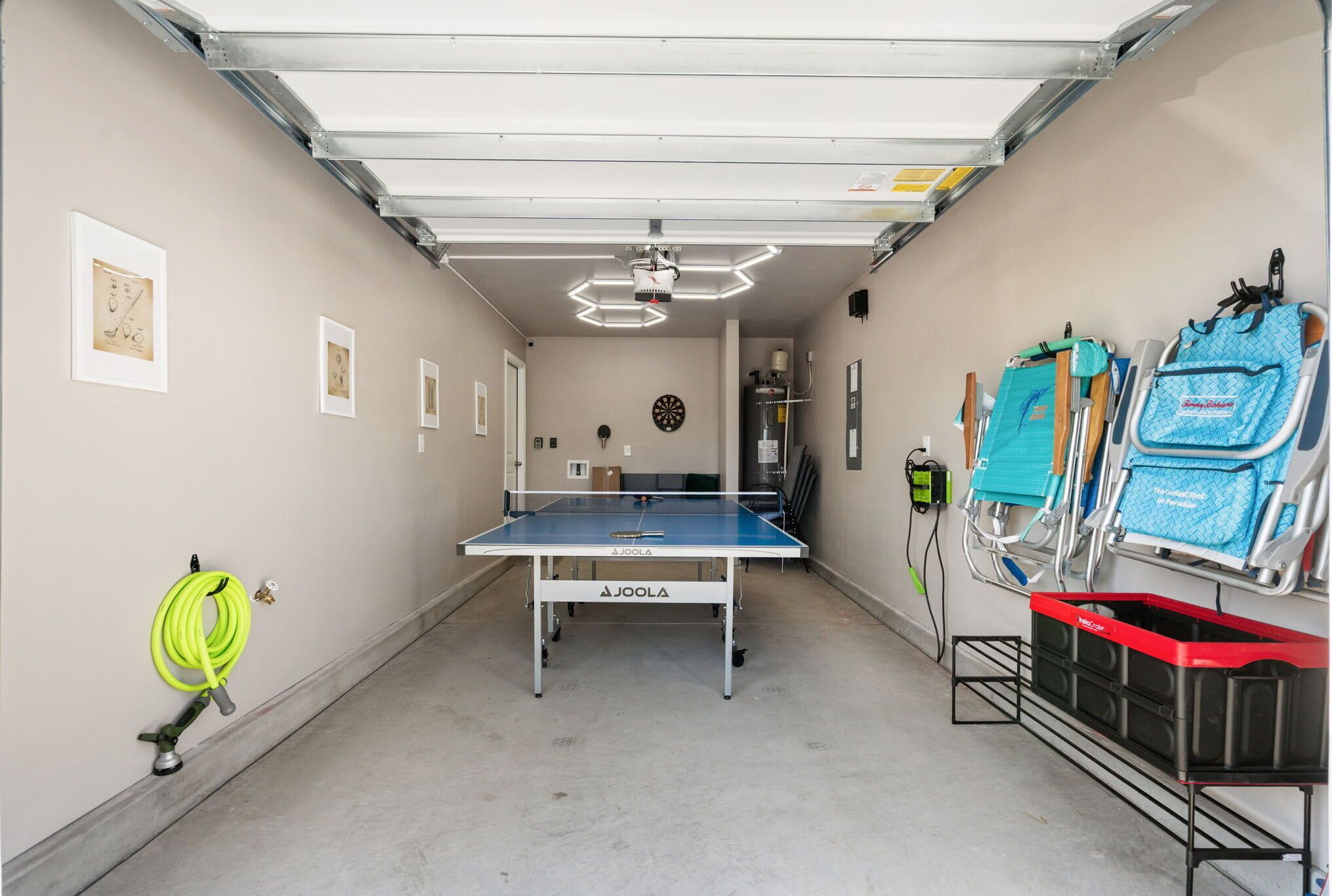 A garage with a ping pong table, a dartboard, and storage shelves.
