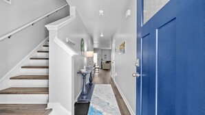 A hallway with a staircase, a blue door, and a rug. - Tide And Tee Ping Pong Golf Cart By Beach Star (Surfside Beach)