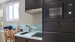 Et moderne køkken med et sort køleskab, indbygget mikroovn, vask og et vindue over bordpladen.