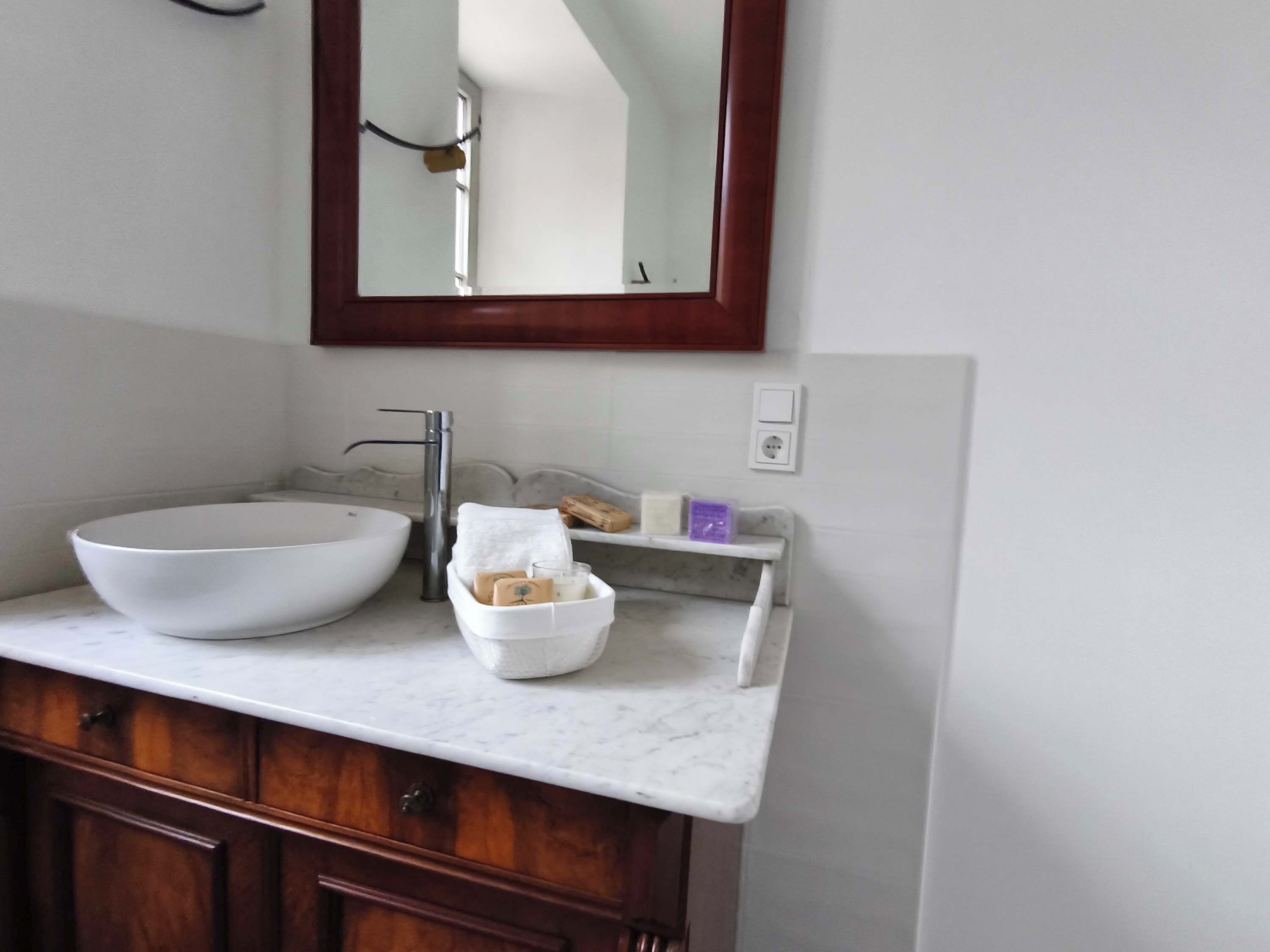 A bathroom with a white sink, a mirror, and a wooden cabinet.
