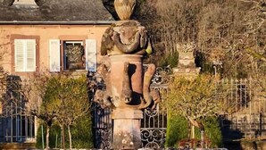 A fountain with a classical design, surrounded by well-maintained greenery and a building with a pitched roof in the background. - Elegance & Charm in Château – Suite Marie Thérèse (Malberg)
