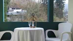 Een tafel met een wit tafelkleed, twee witte stoelen en een decoratieve accessoire met glazen en een klok.