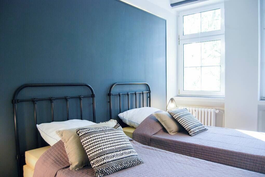 A bedroom with two beds, each with a headboard, and a window providing natural light.