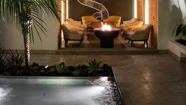 Un salón moderno con una chimenea central, asientos cómodos y una pared decorativa con diseño espiral.