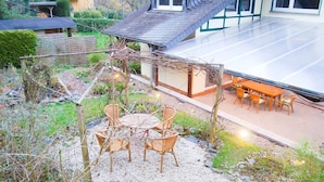 A patio with a table and chairs, surrounded by a garden with a pergola. - The "Wildstein", spring water shower, Thermal spa inkl (Traben-Trarbach)