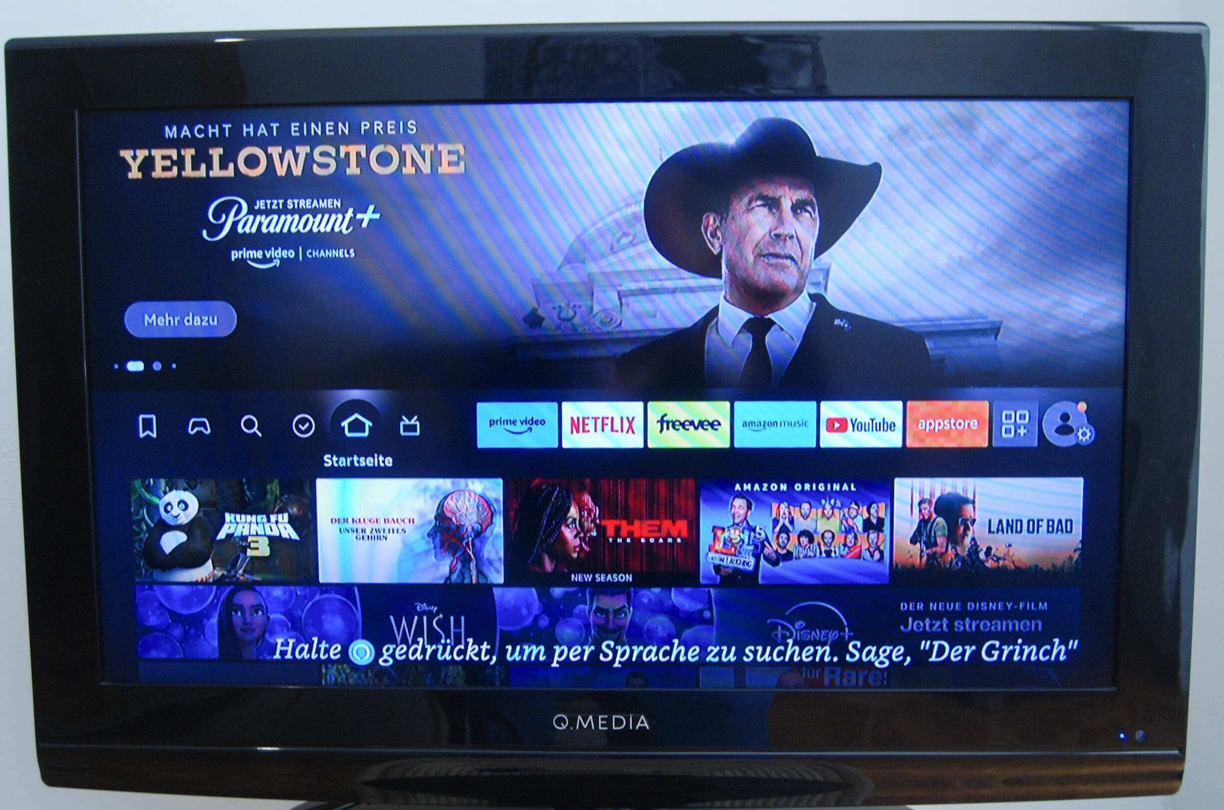 Ein Fernsehbildschirm zeigt eine Streaming-Dienstanwendung mit verschiedenen Filmangeboten und einer hervorgehobenen Werbung für Yellowstone.