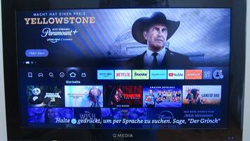 Ein Fernsehbildschirm zeigt eine Streaming-Dienstanwendung mit verschiedenen Filmangeboten und einer hervorgehobenen Werbung für Yellowstone.