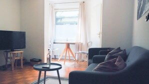 A living room with a TV, a sofa, a small table, and a chair. - The "Wildstein", spring water shower, Thermal spa inkl (Traben-Trarbach)