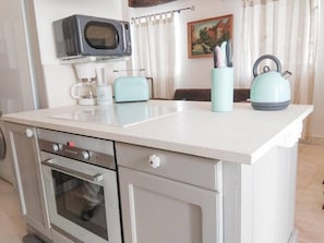 A compact kitchen with a microwave, toaster, kettle, and a coffee maker on the counter. - Living in history: Heidi Braun Cottage (Dudeldorf)