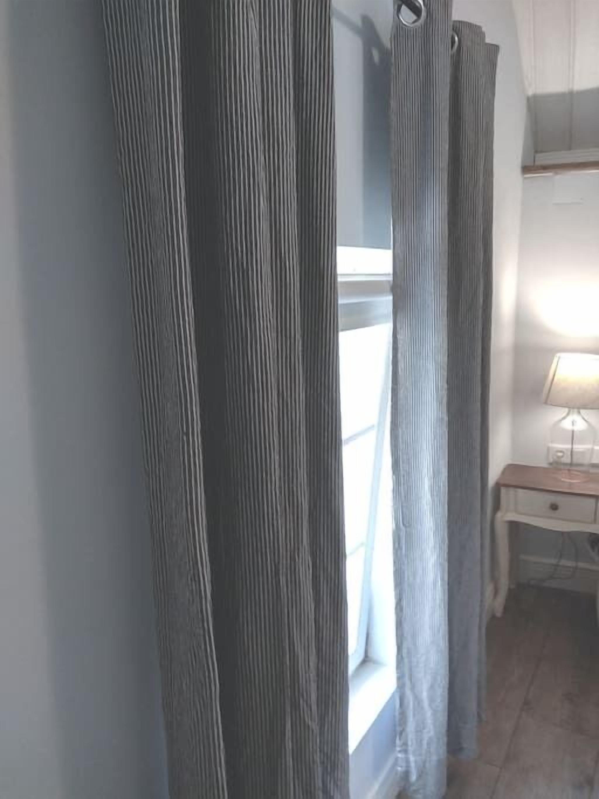A room with a window, a desk with a lamp, and a curtain.