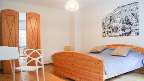 A bedroom with a wooden bed, a white chair, a desk, and a large wall painting. - Small timeout, spring water shower, thermal spa incl. (Traben-Trarbach)