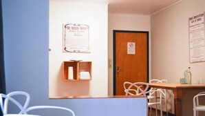A room with a wooden door, a bulletin board with a notice, a small shelf with a cup, and a table with chairs. - Small timeout, spring water shower, thermal spa incl. (Traben-Trarbach)