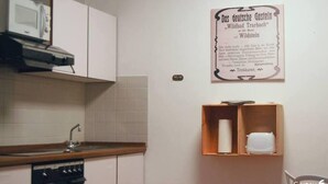 A kitchen with white cabinets, a microwave, and a wooden shelf with a roll of paper towels. - Small timeout, spring water shower, thermal spa incl. (Traben-Trarbach)