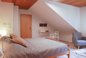 A bedroom with a bed, a desk, and a chair.
