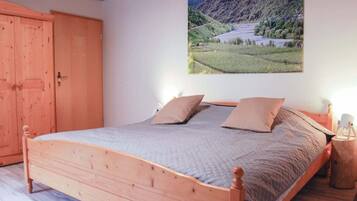 Un dormitorio con cama de madera, un ventanal grande y un cuadro de un paisaje en la pared.