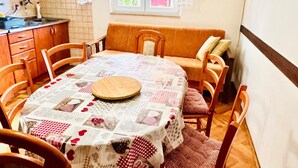 A dining area with a round table covered in a patchwork tablecloth, surrounded by wooden chairs. - Spacious Stone Villa With Sea Views (Dubrovnik)