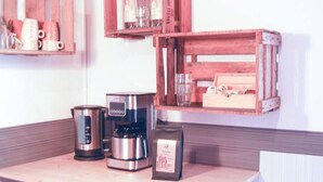 Una encimera de cocina con una cafetera, un hervidor y un paquete de café.