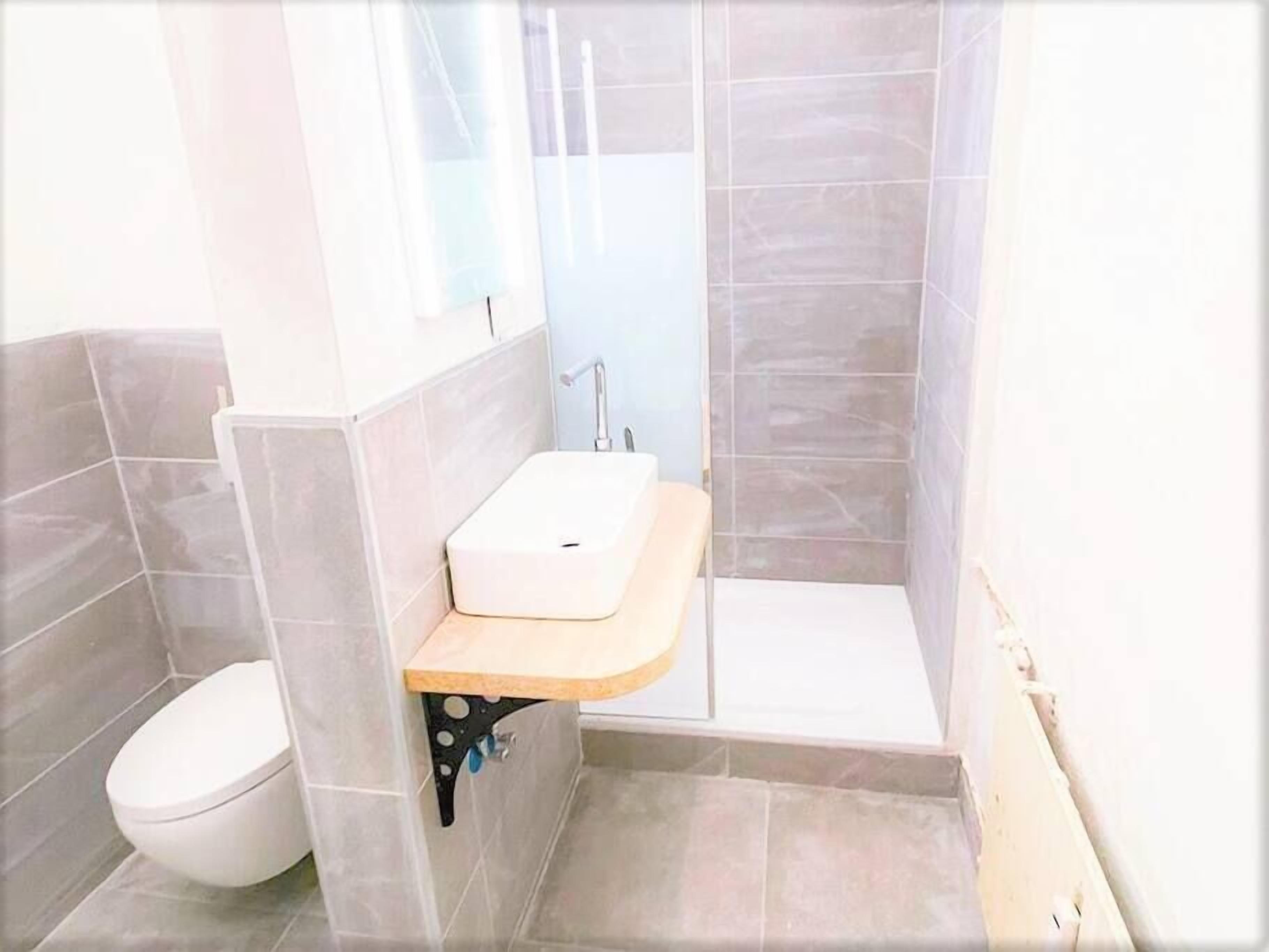 Ein kleines Badezimmer mit Toilette, einem Holzwaschtisch mit Waschbecken und einer Duschkabine.