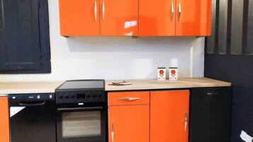 Eine Küche mit schwarzen und orangefarbenen Schränken, einem Geschirrspüler, einem Backofen und einem Herd.