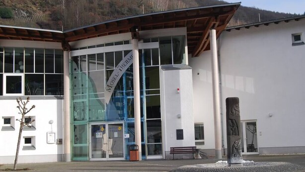 A modern building with large glass windows, a prominent sign reading "MUSEUM," and a stone sculpture in front. - Quiet, spacious room, priv. Bathroom, spring water (Traben-Trarbach)