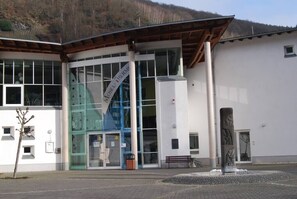 A modern building with large glass windows, a prominent sign reading "MUSEUM," and a stone sculpture in front. - Quiet, spacious room, priv. Bathroom, spring water (Traben-Trarbach)