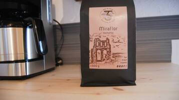 A bag of coffee labeled 'Miraflor' with a weight of 500g, placed on a wooden surface next to a stainless steel appliance.