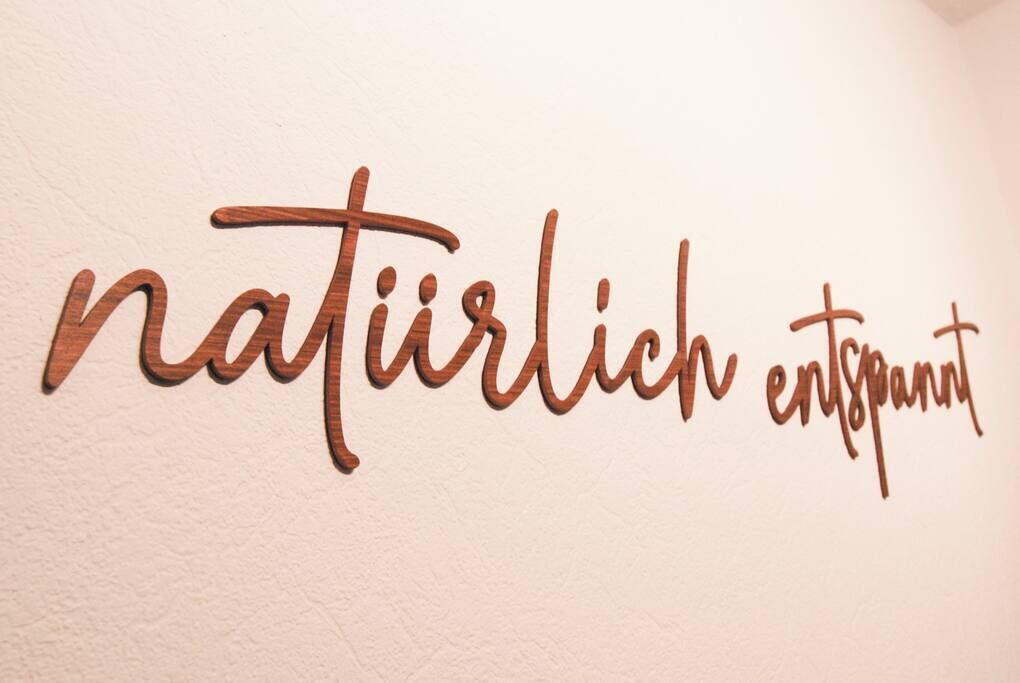 Una pared con el texto "naturlich entspann" en una tipografía de madera.