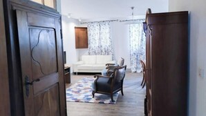A spacious living room with a white sofa, a patterned rug, and a wooden cabinet.
