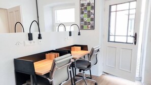 A modern office space with a long table, four chairs, and two black desk lamps.