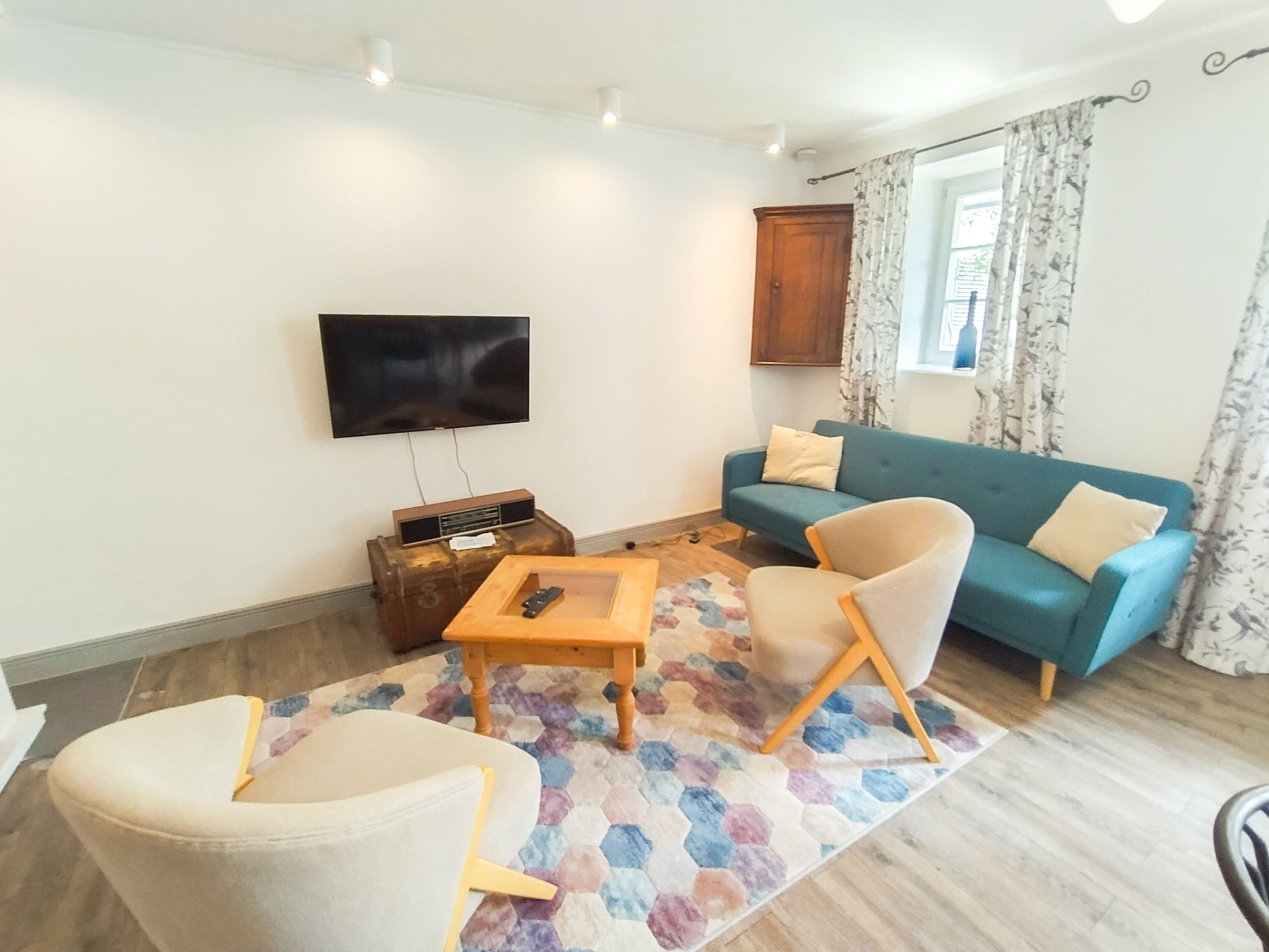 Un salon comprenant un canapé, des fauteuils, une table basse, un téléviseur et un meuble.