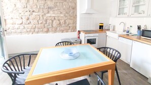 A compact kitchen with a stone wall, a dining table with chairs, and a microwave.