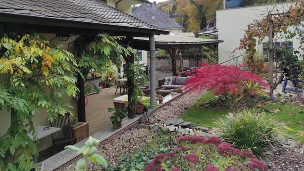 A garden with a patio area, potted plants, and a stone pathway. - Relax and comfort, spring water shower, thermal spa incl. (Traben-Trarbach)