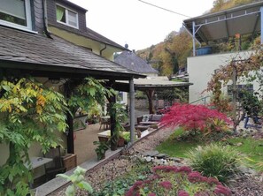 A garden with a patio area, potted plants, and a stone pathway. - Relax and comfort, spring water shower, thermal spa incl. (Traben-Trarbach)