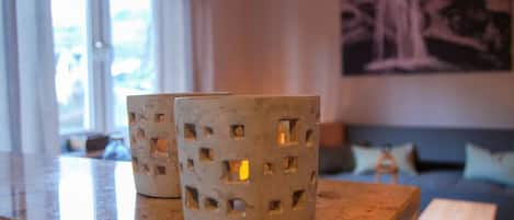 Two candle holders on a wooden counter in a room with a blue sofa and a painting of a waterfall on the wall.