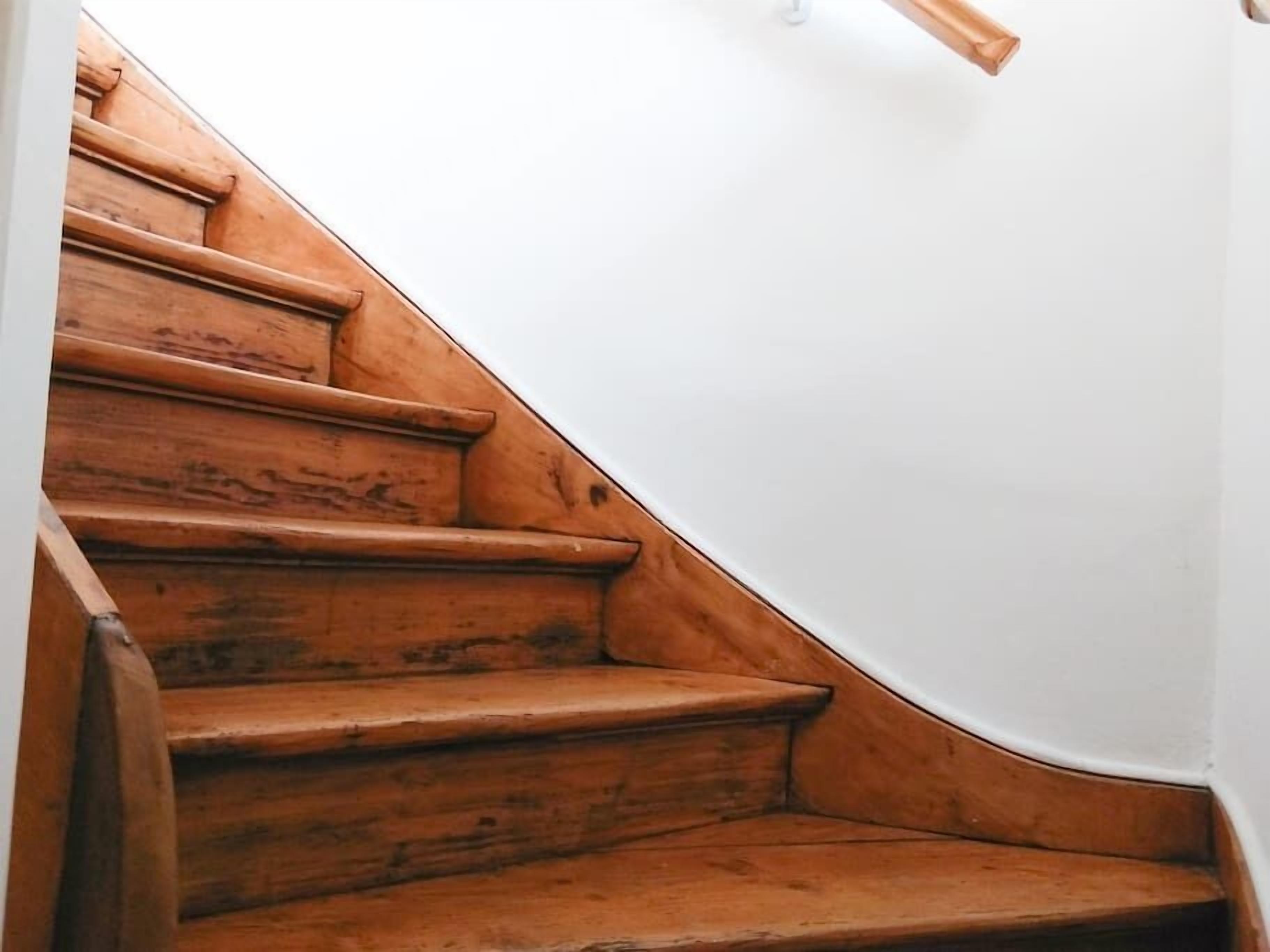 A wooden staircase with a white wall at the top.