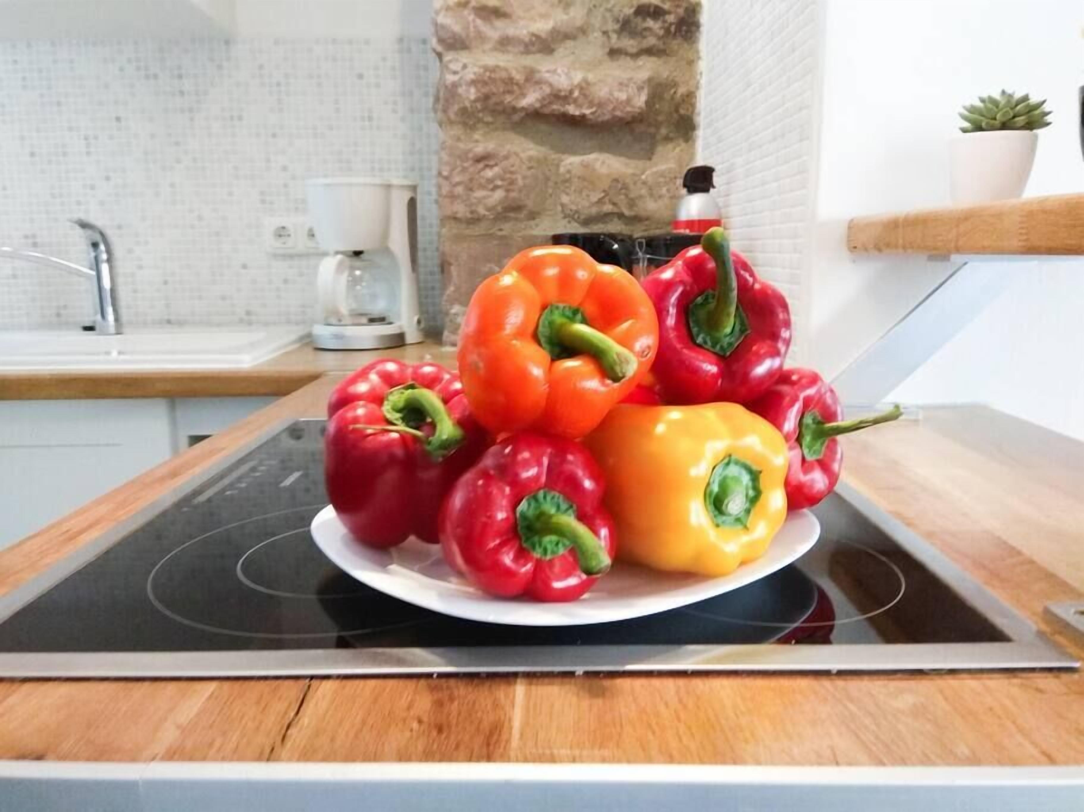 A kitchen with a stove, a sink, and a stone wall.