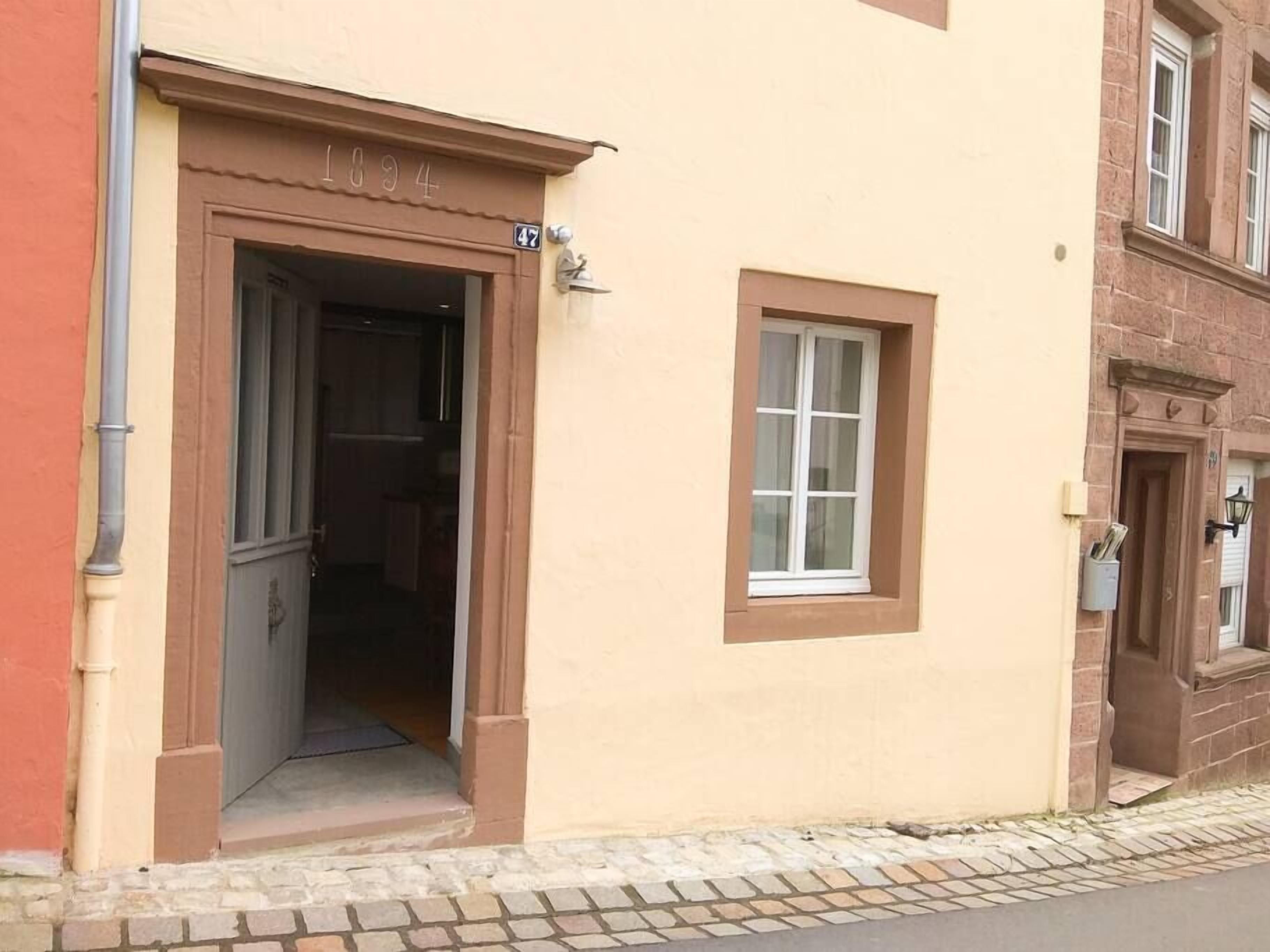 Un edificio con facciata beige, ingresso a cornice marrone e una piccola finestra.