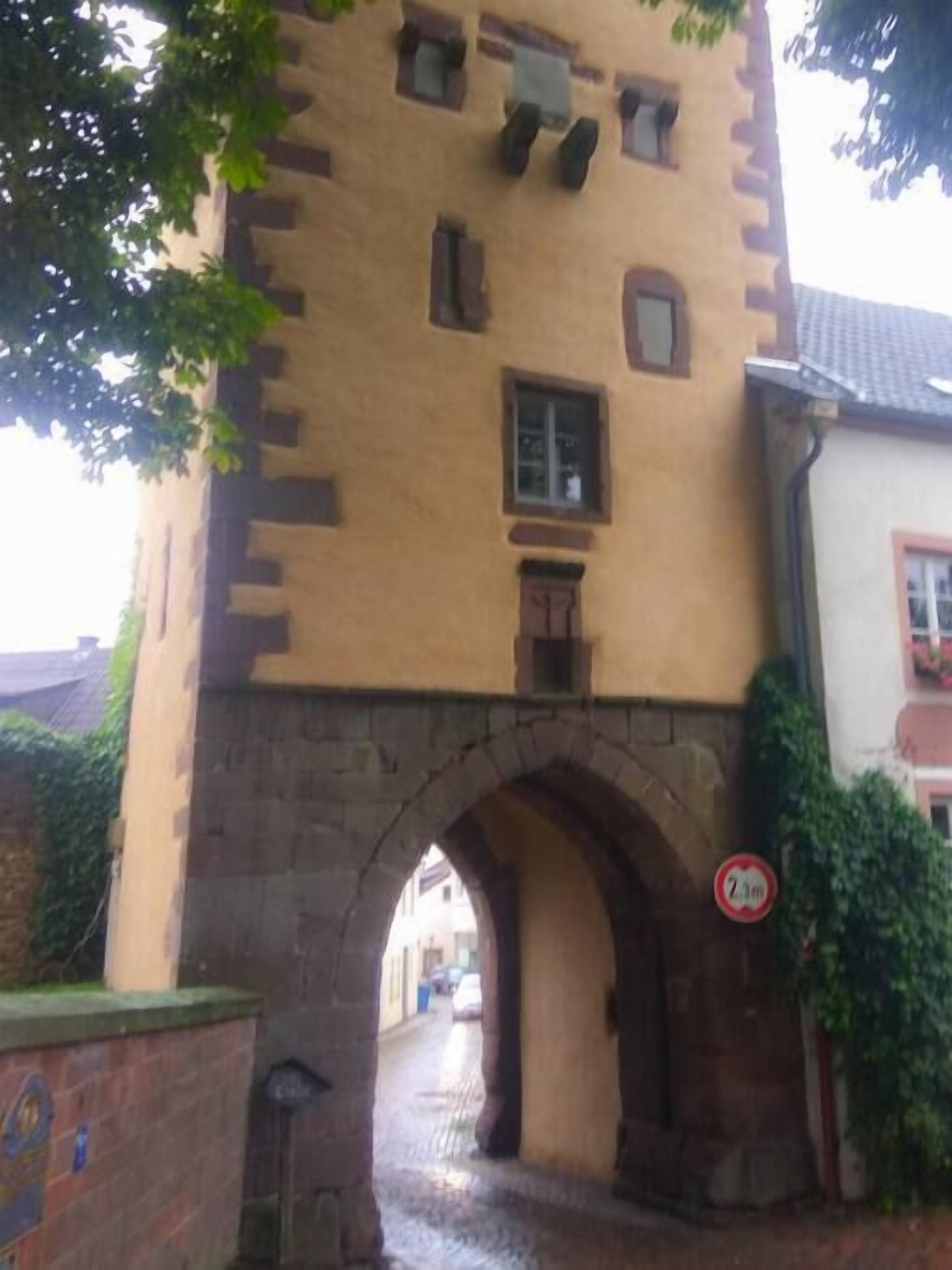 Un bâtiment de style médiéval, doté d’une arche en pierre, d’une petite fenêtre et d’une porte.