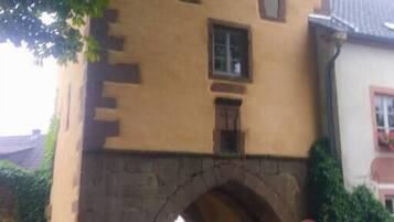 Un bâtiment de style médiéval, doté d’une arche en pierre, d’une petite fenêtre et d’une porte.