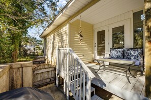 A porch with a white railing, a bench, and a hanging bird feeder. - Walk to Beach in OKI with Hot tub, & Pet Friendly (Oak Island)