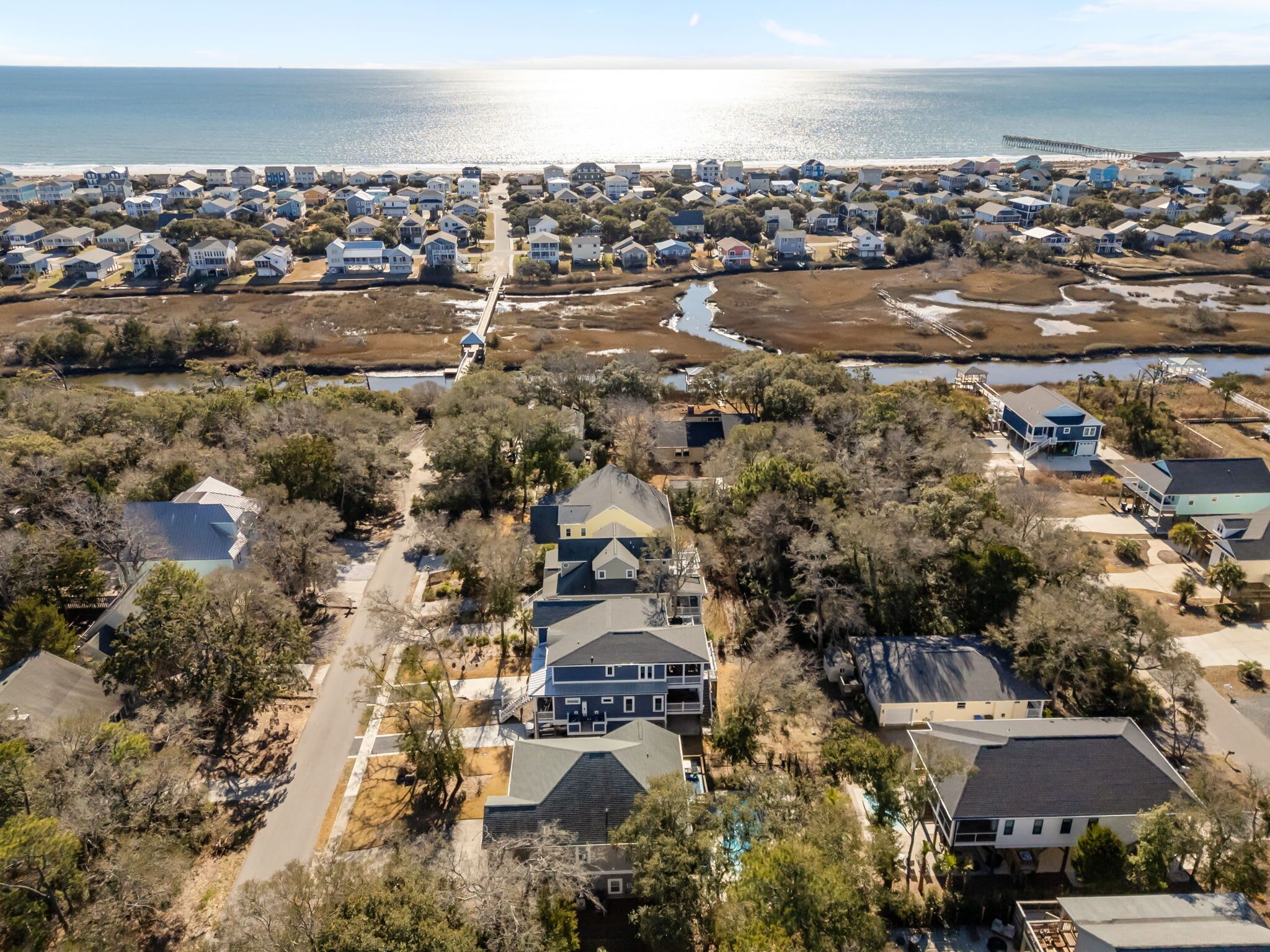 Vista aérea de una zona residencial costera con casas, un muelle y una playa.