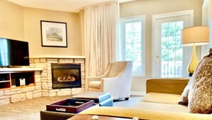 Una sala de estar con chimenea de piedra, televisor, sofá y lámpara.
