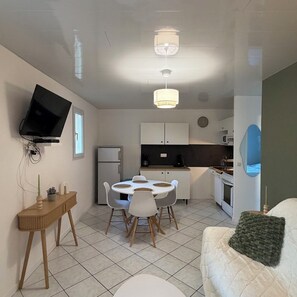 A compact living space with a dining area, kitchenette, and a TV mounted on the wall. - Vacation home 3* - Sous les pins (Ozillac)