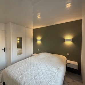 A bedroom with a bed, a wardrobe, and two wall-mounted lights. - 3-Star Vacation Home - Sous les pins (Ozillac)