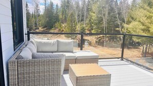 A balcony with wicker furniture and a view of a forest. - Heated pool & Nature - Red door (Saint-Côme)